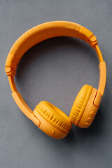 Children's wireless headphones yellow on a gray background. Music and technology.