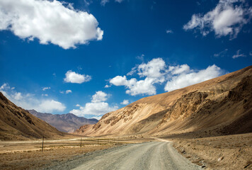 A road winds through a desert with a clear blue sky above