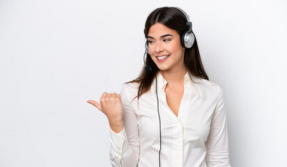 Telemarketer caucasian woman working with a headset isolated on white background pointing to the...