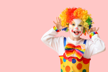 Little girl in clown costume grimacing on pink background. April Fools' Day celebration