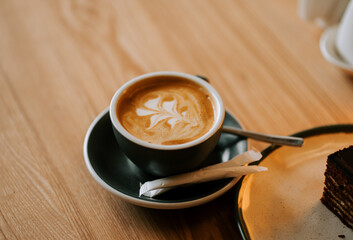 Warm latte art in a cozy cafe setting with delicious dessert on the side