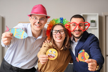 Young colleagues with funny disguise and papers in office. April Fools' Day celebration