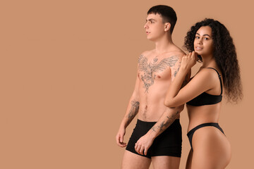 Young couple in stylish underwear on beige background