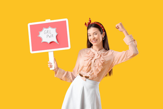Young pin-up woman with GRL PWR sign showing muscles on yellow background. Women's History Month - Powered by Adobe