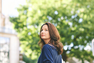 Outdoor portrait of beautiful mature 40 year old woman with brown hair, looking back over the shoulder