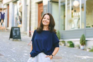 Outdoor portrait of happy mature woman posing on the street, urban lifestyle