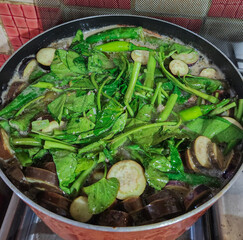 Pork Sinigang topped with chopped water spinach and eggplant.