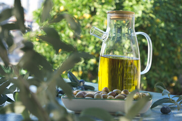 Olive oil in glass bottle and fresh olives on table