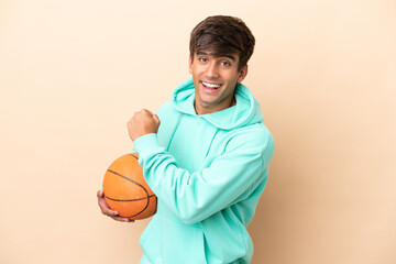 Handsome young basketball player man isolated on ocher background celebrating a victory