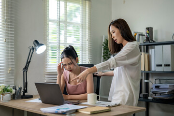A woman is sitting at a desk with a laptop and a cup of coffee