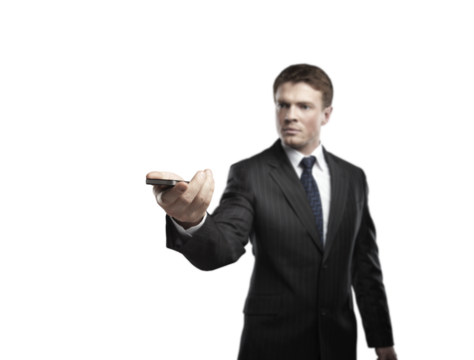Businessman in a formal suit holding a smartphone, extending his hand forward, isolated on a white background. Concept of technology and communication