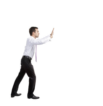 A man in formal attire, appearing to push an invisible object with both hands, isolated on a white background. Concept of effort or resistance
