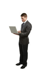 A businessman in a formal suit using a laptop while standing, isolated on a clean white background. Concept of professionalism and technology