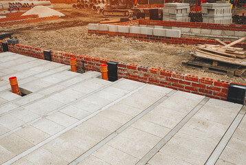 Construction site showing foundation work with concrete blocks and drainage pipes in a developing area during daylight
