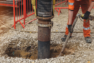Construction worker uses a vacuum excavator to break ground for exposing underground services in...