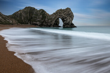 Beautiful atmospheric landscape image of rock arch and cliffs on Jurassic Coast in England during Winter sunset