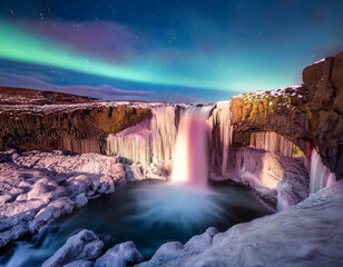 Aldeyarfoss waterfall in winter with polar lights