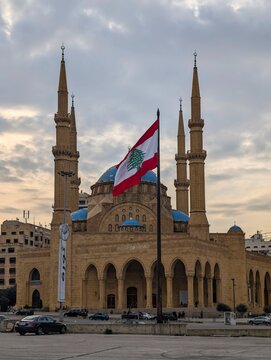 Beirut, Lebanon 01 26 2025: Al Amin mosque with blue domes alongside Christian church with a cross in downtown Beirut. Lebanese flag prominent. Diversity, religious coexistence, and national identity.