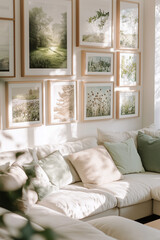 Fototapeta premium Stylish modern living room interior with many picture frames hanging on the wall above a sofa. Cozy living room arrangement with big window, soft blankets and pillows and house plants.