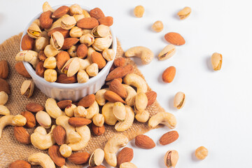 Large assortment of nuts in different bowls on stone table.