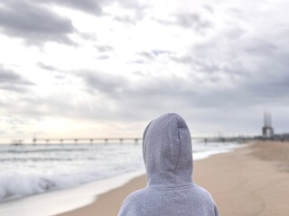 Silence and mystery: Hooded person looking at the sea.