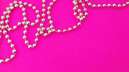 Silver bead necklace on a pink background