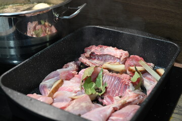 Roasted Rabbit Pieces with Vegetables in a Black Roasting Pan