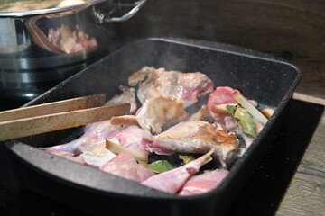 Roasted Rabbit Pieces with Vegetables in a Black Roasting Pan