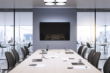 Modern conference room with a long table, laptops, and chairs in a corporate office setting. Minimalist design with a large display screen. 3D Rendering