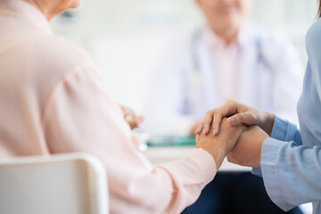 Focus at woman hold her mum hand to give encouragement while see doctor at hospital blur doctor ground.