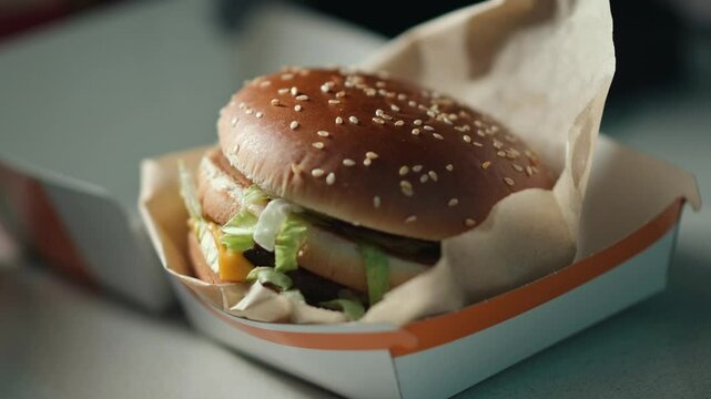 Delicious burger presentation featuring fresh lettuce and melted cheese in a simple takeout box