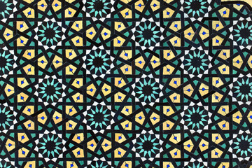 A detailed Islamic geometric mosaic featuring vibrant colors and symmetrical patterns. The design showcases traditional arabesque motifs with star shapes and interwoven lines