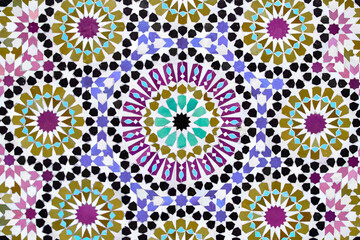 A detailed Islamic geometric mosaic featuring vibrant colors and symmetrical patterns. The design showcases traditional arabesque motifs with star shapes and interwoven lines