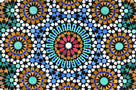 A detailed Islamic geometric mosaic featuring vibrant colors and symmetrical patterns. The design showcases traditional arabesque motifs with star shapes and interwoven lines