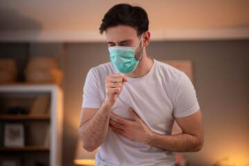 Portrait young ill man in medical protective face mask coughing or sneezing a lot and feeling bad. sick man patient with chest pain
