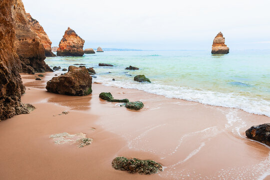 Yellow sandstone rocks on the coast of Atlantic ocean in Algarve, Portugal. Beautiful seascape at foggy morning.