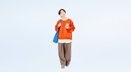 スマホを持って歩くおしゃれなミドル女性の全身写真