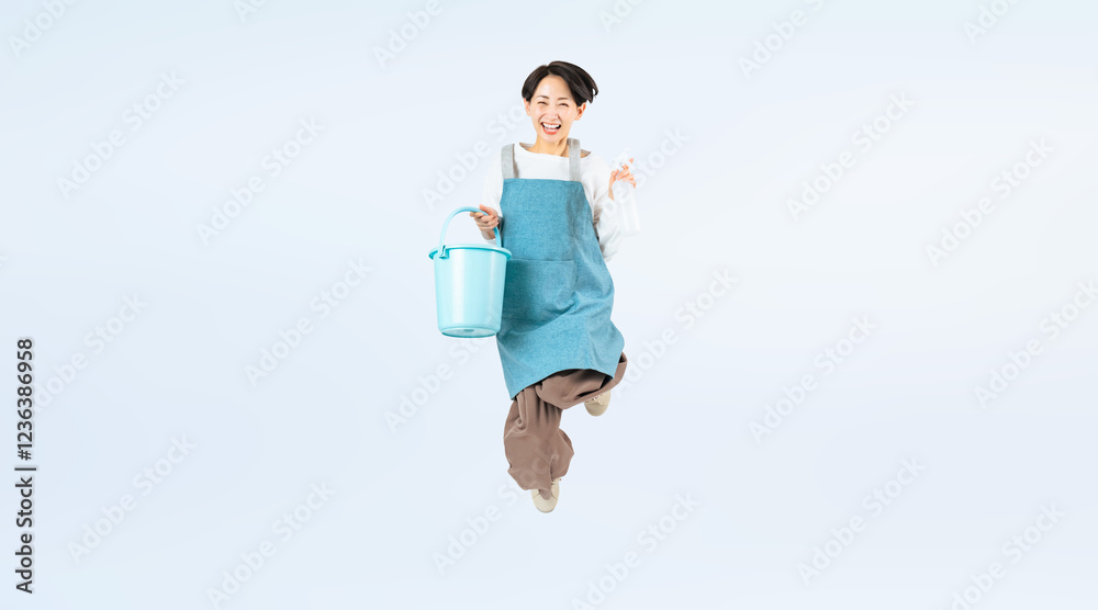 Aufkleber 清掃道具を持ってジャンプするエプロンをつけたミドル女性の全身写真