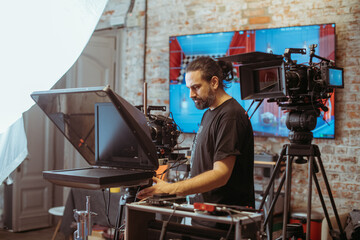 Director of photography with a camera in his hands on the set. Professional videographer at work on filming a movie, commercial or TV series. Filming process indoors, studio