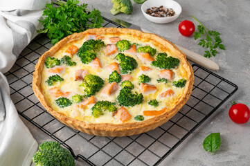 Homemade tart or quiche with salmon, broccoli, cheese and cream filling on a gray stone background. Healthy food. Selective focus.