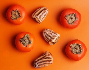 fresh and dried persimmon on orange background