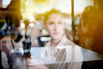 Portrait, window and woman with cup, cafe and relax with drink in morning, reflection and consumer. Glass, customer and person with tea for breakfast, enjoy and warm beverage for break in coffee shop