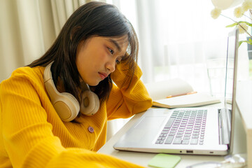 Frustrated Asian young girl student learning online class study in house. Teenage woman feel tired...
