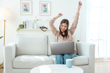 Young Woman Enjoys Working on a Laptop While Sipping Coffee in a Cozy Living Room Setting