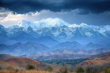 Fototapeta premium Majestic mountain range under dramatic sky with clouds and snow-capped peaks at twilight