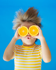 Funny kid with his hair standing on end. Surprised child holding slices of orange