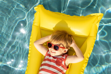 Happy child having fun on summer vacation. Funny kid playing in swimming pool.