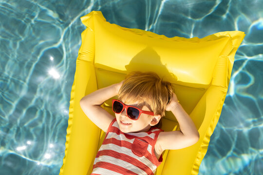 Happy child having fun on summer vacation. Funny kid playing in swimming pool.