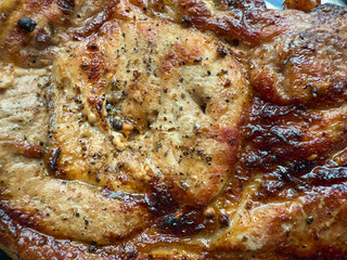 Appetizing piece of fried meat with a browned crust and juicy texture. Seasonings and oils are visible on the surface.