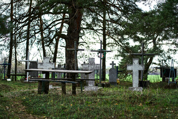 Graveyard with old weathered tombstones and crosses surrounded by trees greenery peaceful serene...
